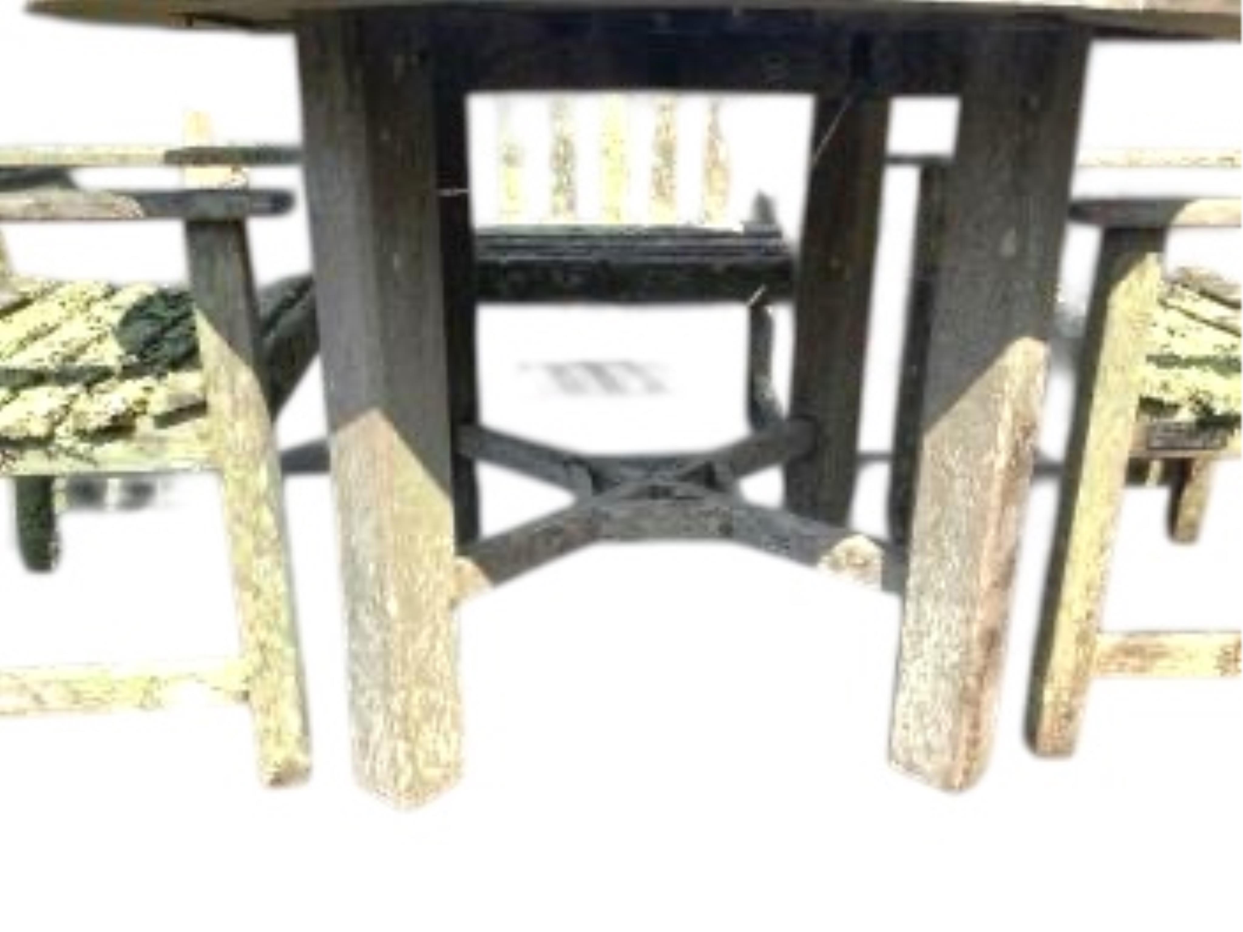 A weathered and lichen covered circular teak garden table, diameter 120cm, height 75cm and four armchairs